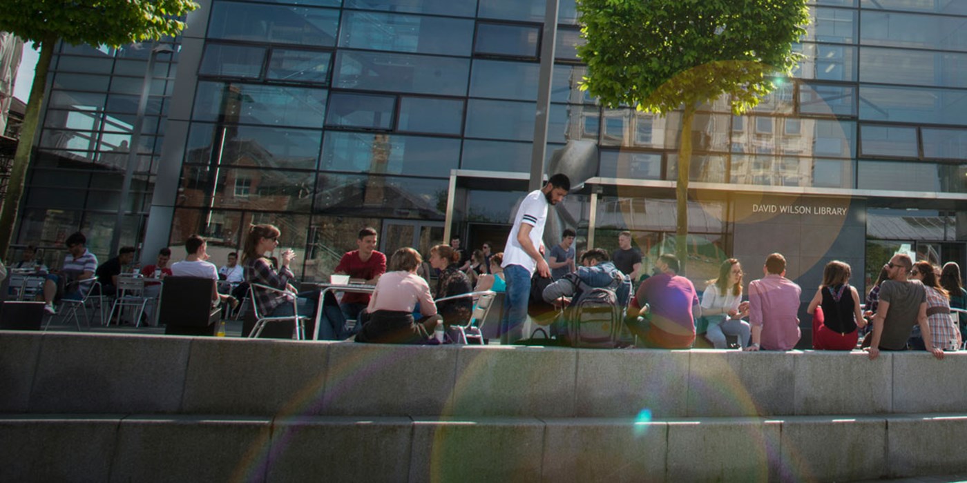 Lots of students sat outside the David Wilson Library on a sunny day