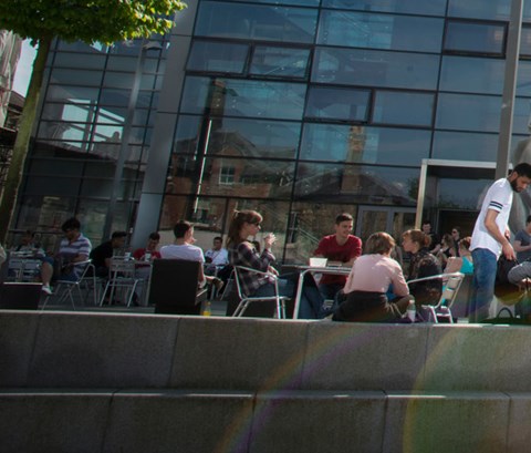 Lots of students sat outside the David Wilson Library on a sunny day