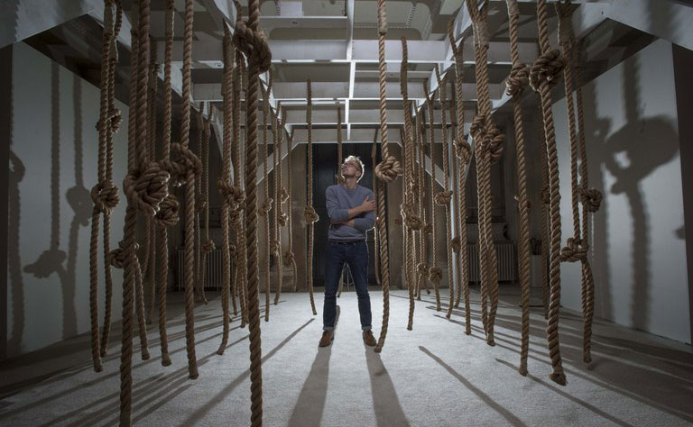 Man looking at ropes hanging from ceiling (EXILE art installation)