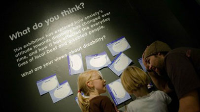 People looking at an exhibition display about disability