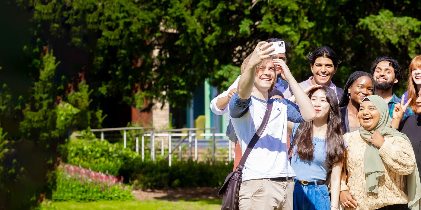Students taking a selfie in a green area on University of Leicester campus