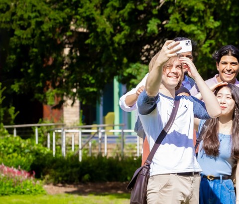 Students taking a selfie in a green area on University of Leicester campus