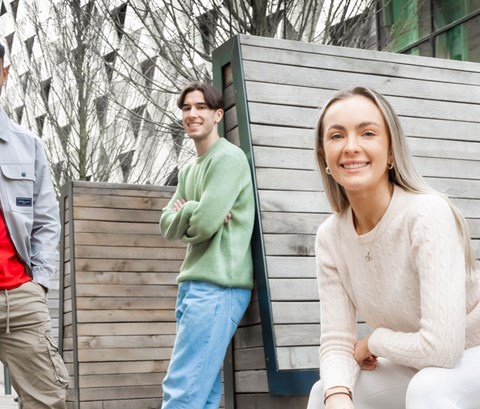 Students sitting on benches and posing for photos on Leicester campus.