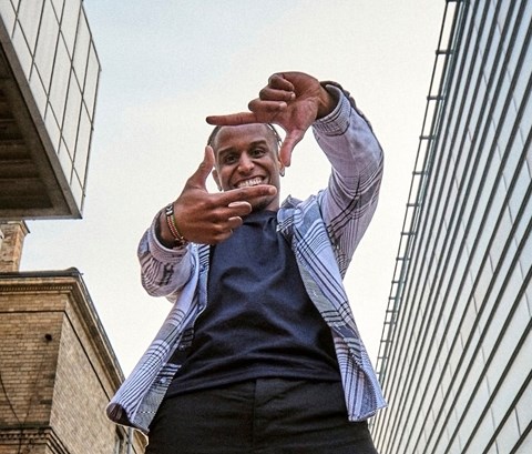 Student on Leicester campus posing to the camera and making a rectangle with his fingers.