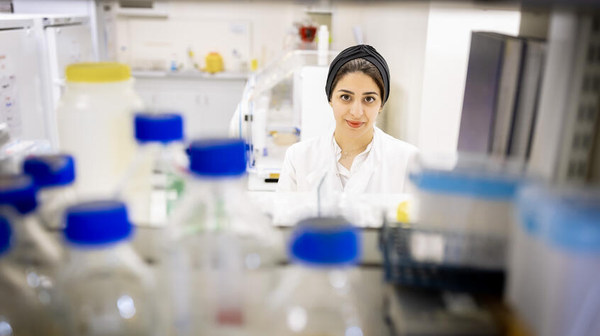 Researcher in lab selecting samples, central and facing camera