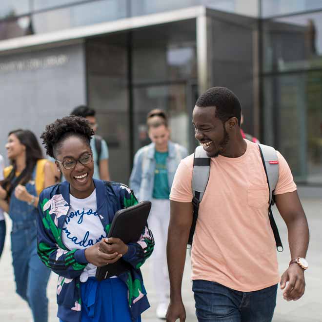 Students laughing together walking out of the library