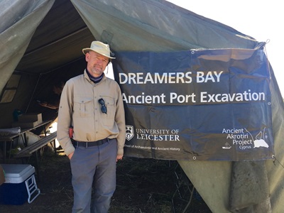 David Ulke stands in front of an excavation tent labelled "Dreamers Bay Ancient Port Excavation"
