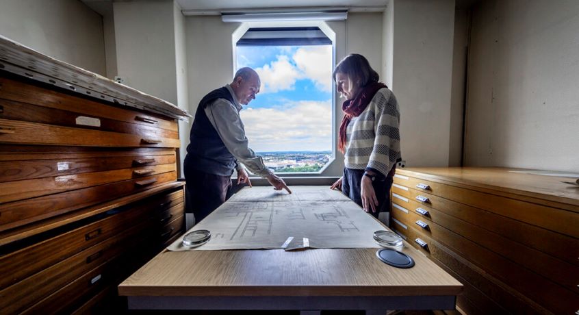 Two people  looking at a large document laid out on a table