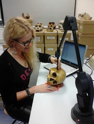 A researcher examining a human skull with a large piece of lab equipment