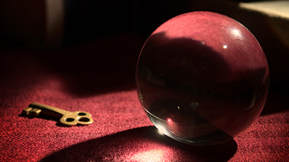 Crystal ball on a red cloth, next to a key and some mysterious books in the background
