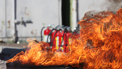 Burning fire in the foreground, in front of a row of fire extinguishers