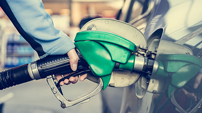 Close up image of a green fuel pump filling a car with fuel