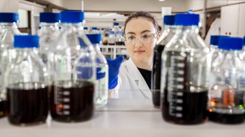 Female researcher selecting chemicals in bottles from a shelf