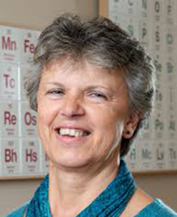 Photograph of Professor Gill Reid, standing in front of a periodic table