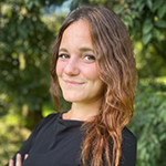 Photograph of Federica Arrigoni, smiling, standing in front of a green tree.