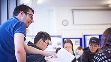 staff member talking to a group of students in class