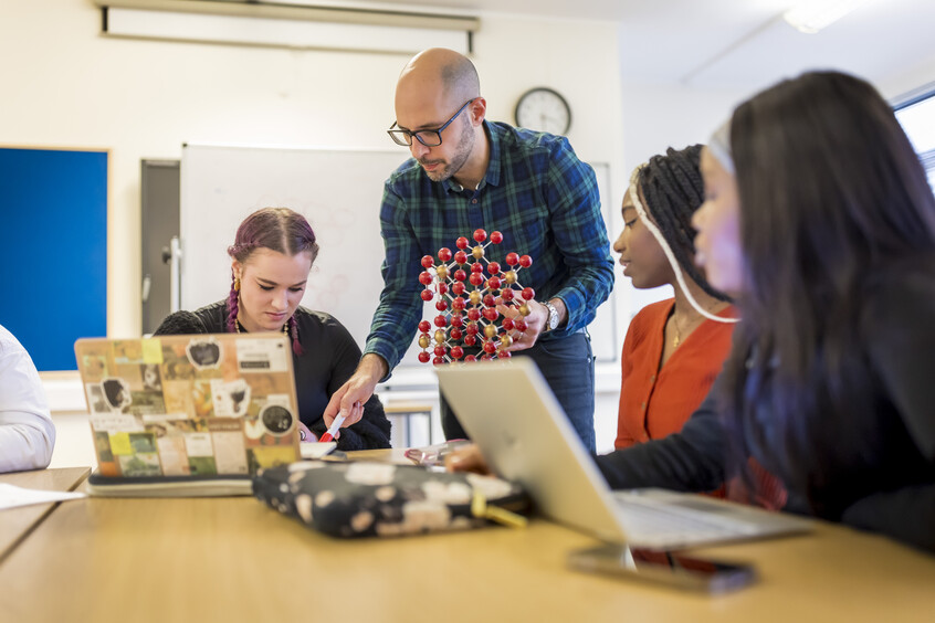 Three female Chemistry students studying with a lecturer.