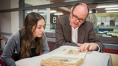 staff and student looking through an old book