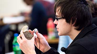 a student looking closely at a rock