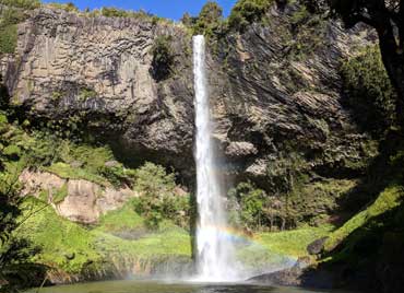 waterfall over rock formation in new zealand