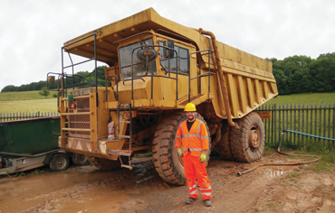 alex standing in front of a huge yellow truck