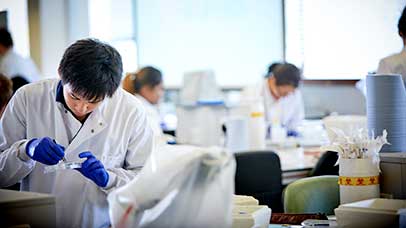 student working in a lab with others in the background