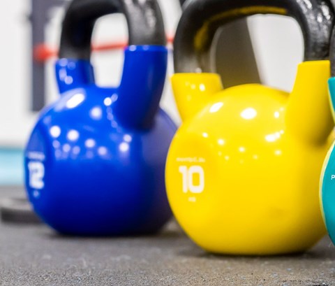 A row of colourful and different sized kettlebell weights