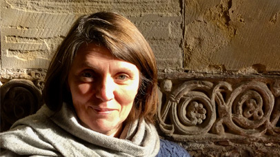 Professor Jo Story standing by a wall inside an Anglo-Saxon church