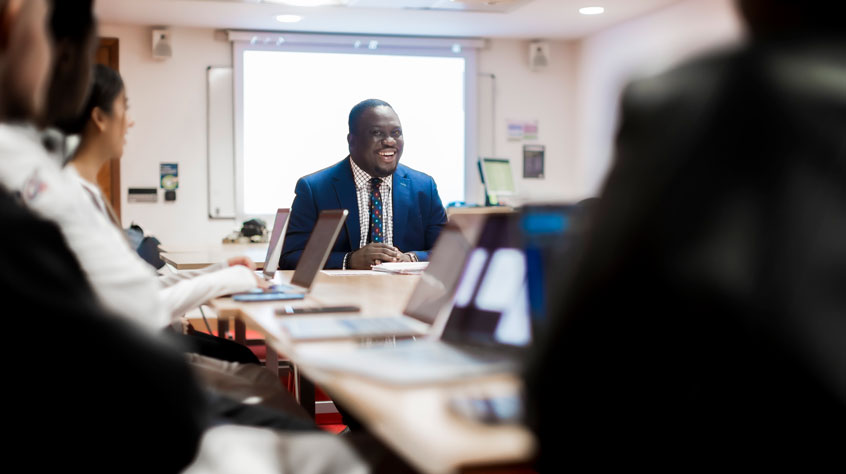 Law student wearing a suit and sitting at a table, smiling.
