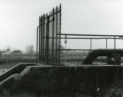 Black and white photograph of the end of a train platform ending in a fence of tall spiked poles, with focus on the angles and lines