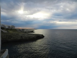 Coastline and ocean in dim light with the sun behind clouds and much of the landscape in shadow