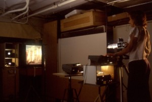 Photograph of artist Nancy Goldring shooting projections in her darkened art studio