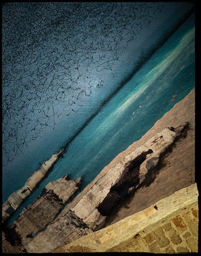 Photographic artwork based on coastal seascape featuring jagged rocks, deep and dark colour contrast between ocean, beach, rocks and stone wall