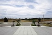 Photograph taken from a raised concrete patio, sitting animal statues either side of some stairs looking out to fields