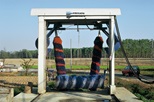 Photograph of a drive-through car wash machine with striped and coloured brushes with farmland behind