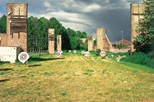 Photograph of a grass landscape with a number of archery targets placed ahead, several brick towers either side and storm clouds in the background