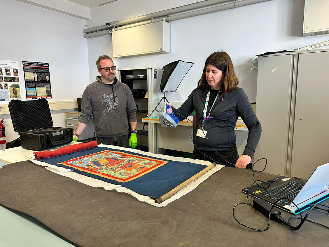 Ben Abbot from Kedleston Hall and Dr Rachel Armitage, Technical Services Manager for the School of Heritage and Culture, examining a Tibetan thangka using scientific analytical methods in the laboratories of the University of Leicester.