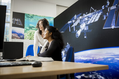 Research students talking about their working in front of a really big picture of a satellite