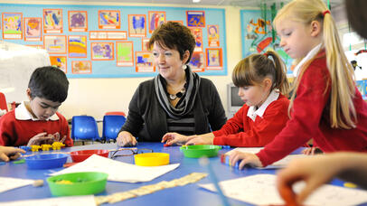 Teacher doing craft activities with primary school pupils