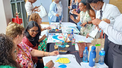 People sat around a desk with arts and crafts on it.