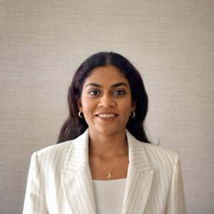 Woman wearing a white suit and smiling to the camera