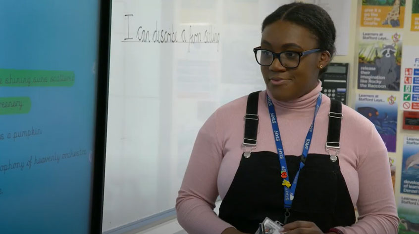 PGCE student at the front of a primary school classroom teaching students