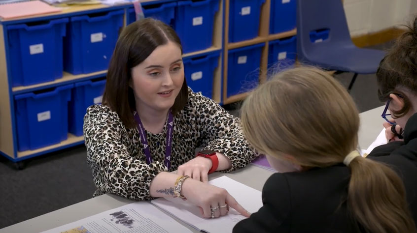 PGCE student in a classroom talking to secondary school students