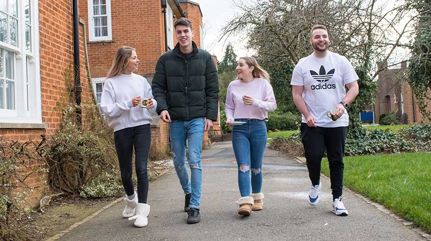 An external shot of Knighton Court student accommodation with four students