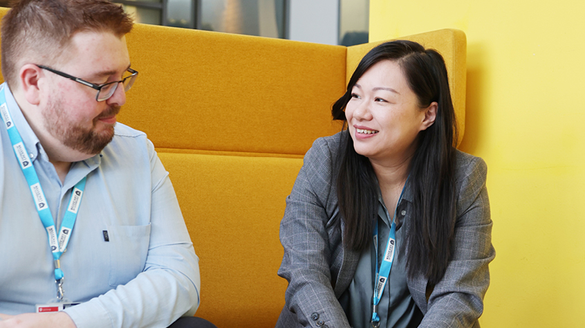 Two colleagues sitting in a booth and discussing ideas in a modern university workspace.