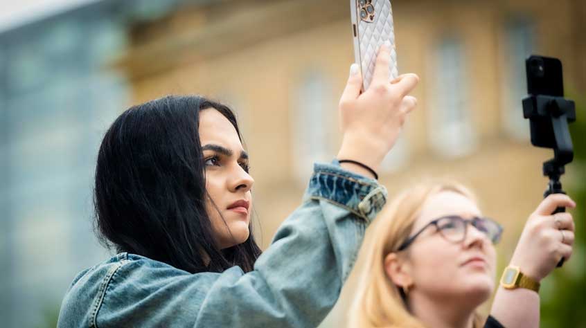 Two people holding up phones taking images at the centenary launch