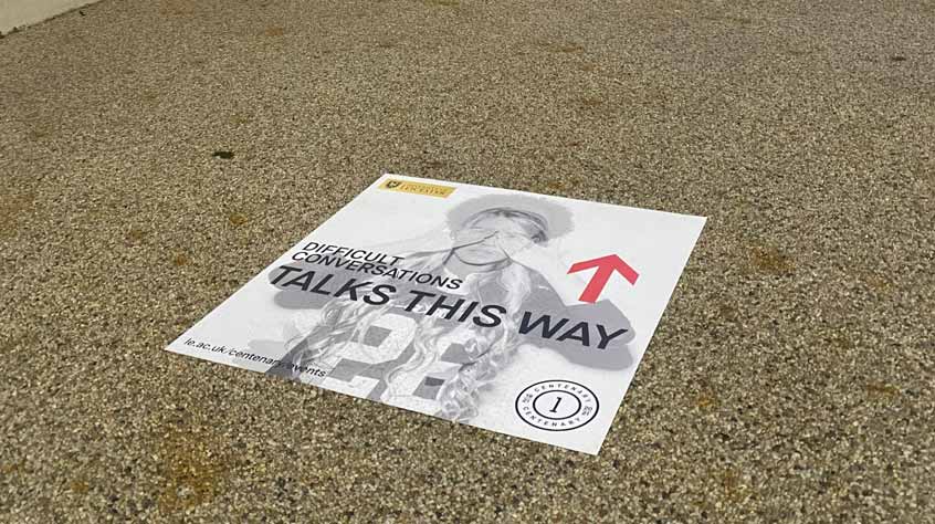 Difficult conversations sign on floor pointing towards where talks are taking place