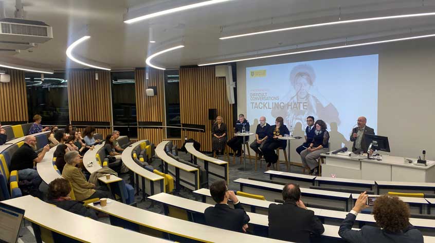 Audience members in a lecture theatre listen to a panel discussion