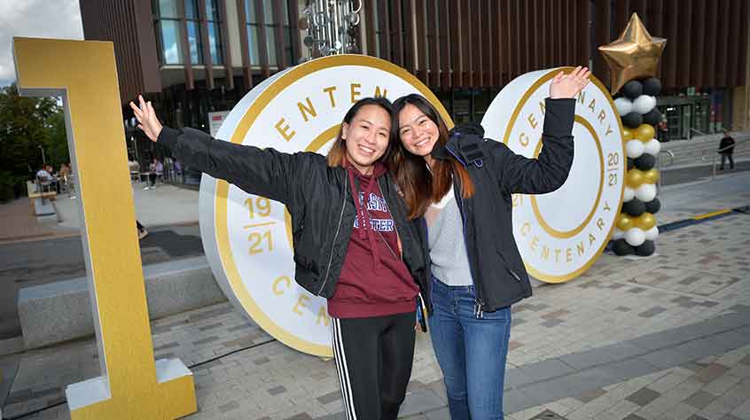 4/10/2021 - 2 students celebrating on campus at the University of Leicester's 100 birthday