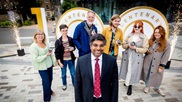 Nishan with people from the centenary launch event in front the centenary sign.